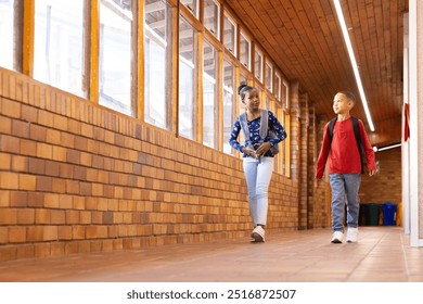 Walking in school hallway, two multiracial boy and girl with backpacks talking and smiling. friends, friendship, conversation, teenagers, happiness, education - Powered by Shutterstock