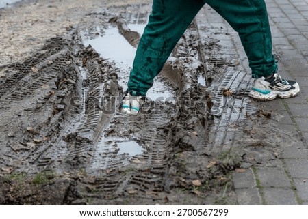 Walking Through Muddy Puddle After Rain — Dirty Sneakers and Tire Tracks Symbolizing Real Life and Imperfection