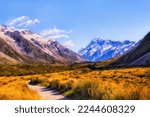 Walking track in Hooker valley to distant Mt Cook in snowcapped alpine mountains of New Zealand.