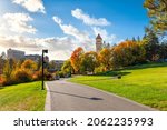 Walking trail and grassy area of Riverfront Park with the clock tower in view as leaves turn fall colors at late autumn in Spokane, Washington, USA