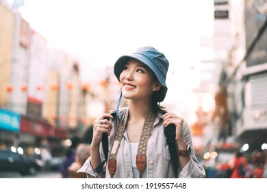 Walking young adult asian woman traveller wear blue hat and backpack. People traveling in city lifestyle at outdoor at chinatown street food market Bangkok, Thailand. Staycation summer trip concept.