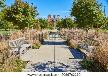Walkway lined with benches and fall grasses leading to old ruins
