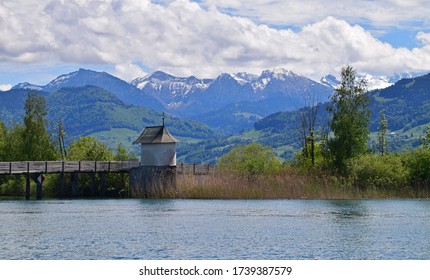 A walkway looking out over lake Obersee with snow capped mountains in the background, taken from Rapperswil, Zurich, Switzerland, on a beautiful spring day