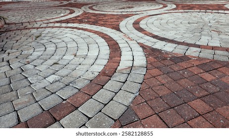 Walkway made of paving slabs in circular pattern as a background. Close up of Red and Grey brick tile floor paving stones. Cobblestone pavement.