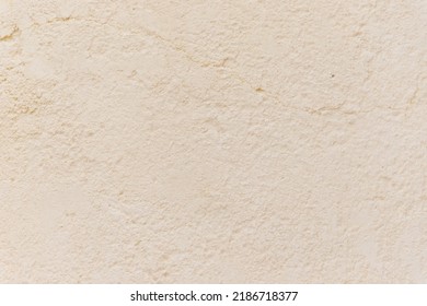 The wall is beige or white. Small cracks on the surface. Texture and background. The old wall. The wall is painted with paint.