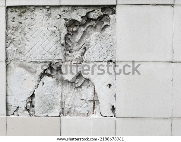 A wall\
with a broken off gray tile from the\
wall