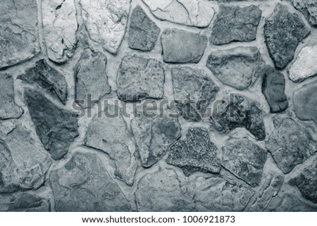 Wall built of natural stone with cement. Toned.