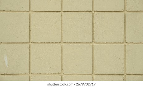 The wall is built of square bricks, rough and plastered, painted light yellow.