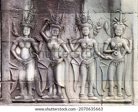 Wall carving with four womans dancers apsara, famous Angkor Wat complex, Siem Reap, Cambodia. Horizontal background with stone texture and bas-relief with dancing girls. UNESCO world heritage site