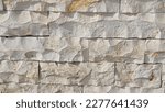 A wall clad with hewn stone. These stone slabs are usually selected for their color and texture, and then machined into regular or irregular shapes to create an aesthetic and natural look.
