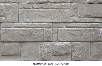 Wall cladding made of rough light gray natural stones with different shapes . Background and texture