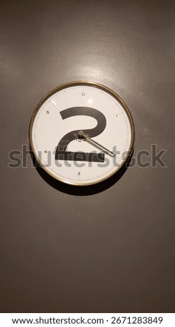Wall clock with a large number two design and simple black hands on a plain background