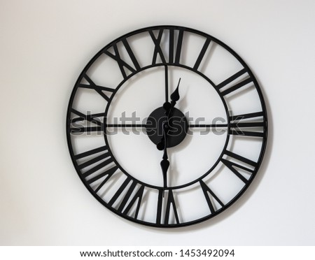 Wall clock on a white background. Twelve o'clock thirty minutes.  12-30 minutes.