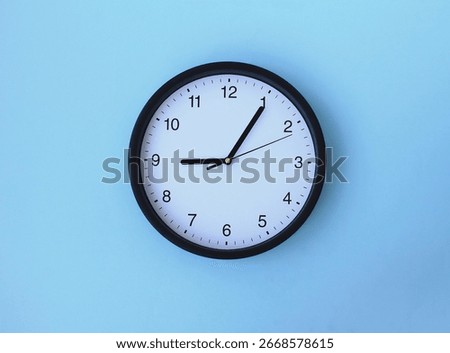 Wall clock. Round clock with black dial isolate on a blue background. Time is running. Close-up.