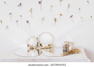 Wall decor featuring a display of dried flowers taped to the wall above a table set with floral wreaths, glass jars filled with dried blossoms, and a bouquet, creating a rustic and elegant atmosphere. - Powered by Shutterstock