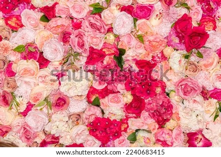 A wall densely covered with dummy roses and other plastic flowers