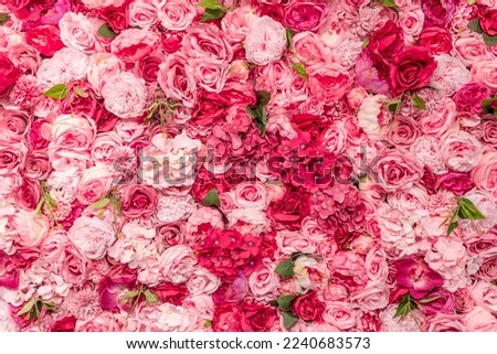 A wall densely covered with dummy roses and other plastic flowers