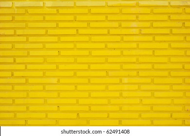 A wall of dirty yellow raised thin bricks