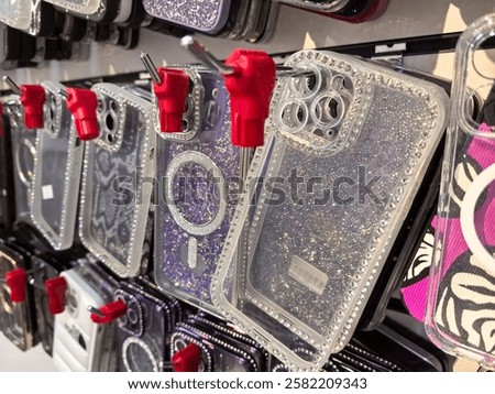 A wall display showcases an array of colorful phone cases glistening with sequins and rhinestones. Each case hangs neatly, attracting attention in a modern retail space.