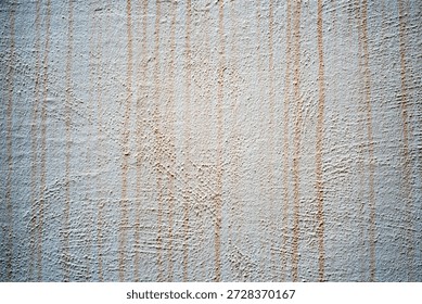 A wall displays a surface with vertical lines and patterns. The light creates different textures, showing simple designs in a quiet space during the day.