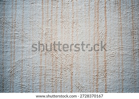 A wall displays a surface with vertical lines and patterns. The light creates different textures, showing simple designs in a quiet space during the day.
