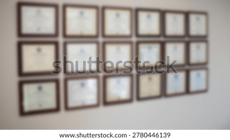 A wall featuring multiple framed certificates and diplomas, likely in an office or professional environment, showcasing achievements and qualifications.