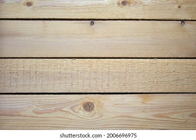 A wall of four pine planks connected and hammered together. The boards are not finished, rough and rough. Are arranged horizontally.