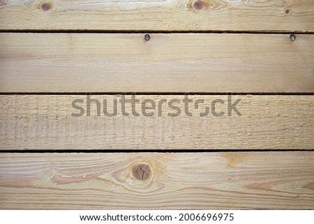 A wall of four pine planks connected and hammered together. The boards are not finished, rough and rough. Are arranged horizontally.