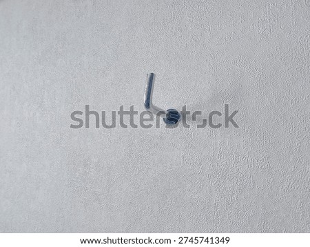 Wall hook fixed on a plain white surface in a simple room setup