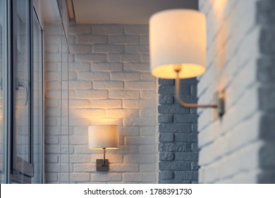 Wall Lamp In Modern Loft Apartment. Wall Sconce On White Brick Wall. Yellow Lights In Shade. Evening, Lights On.