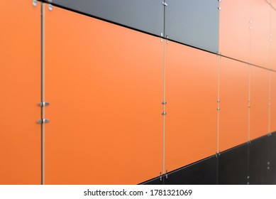 The wall is lined with colored ceramic tiles of orange, gray and black color. Minimalism, background