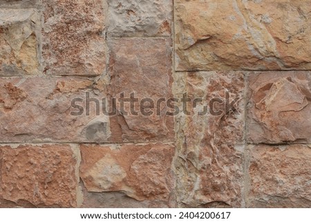 The wall is lined with processed rectangular natural stone with red shades