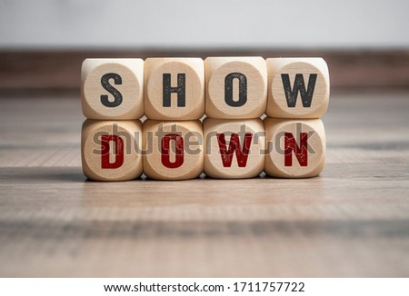Wall made of cubes or dice with message showdown on wooden background