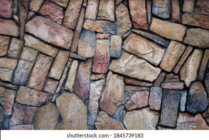The wall is made of multi-colored natural stone, the masonry is stone on cement. Concept - stone wallpaper, background and decor - Shutterstock ID 1845739183