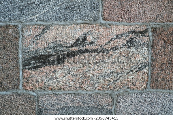 The wall is\
made of rectangular granite blocks. Hewn granite stone with the\
presence of the black mineral biotite. Granite texture, background.\
                             \
