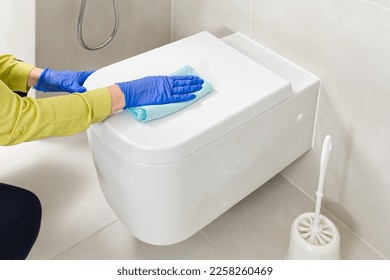 Wall mounted toilet cleaning with detergent. Woman hotel maid cleans a bathroom toilet with a scrub brush. household service. Modern flush toilet. Cleaning - Shutterstock ID 2258260469