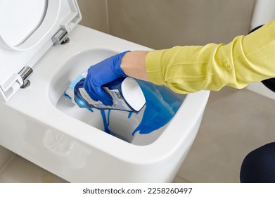 Wall mounted toilet cleaning with detergent. Woman hotel maid cleans a bathroom toilet with a scrub brush. household service. Modern flush toilet. Cleaning - Shutterstock ID 2258260497