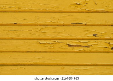 wall of an old bright yellow barn, the paint is peeling off the wall, the idea of wallpaper, the old background