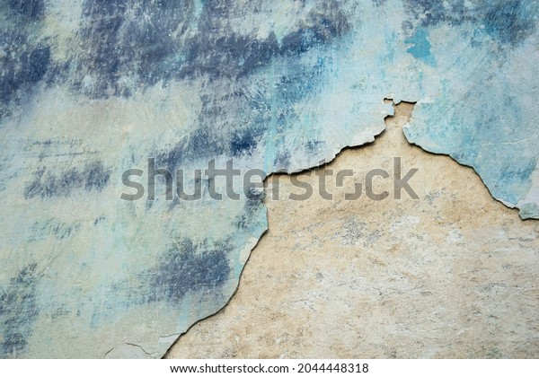 Wall of old building with partially fallen off\
plaster in gray and blue colors. Space is divided into two parts of\
different structures. Abstract background. Copy space. Close-up.\
Selective focus.