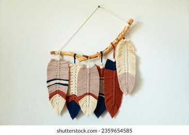 Wall panel in Boho style made of cotton beige, blue and red cords using macrame technique. Modern home decor trend, cozy atmosphere, boho style.