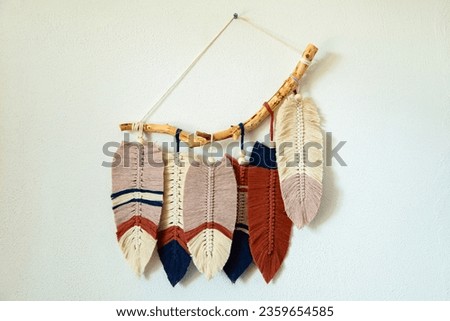 Wall panel in Boho style made of cotton beige, blue and red cords using macrame technique. Modern home decor trend, cozy atmosphere, boho style.