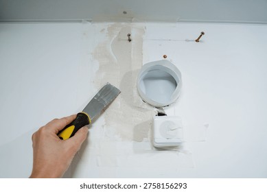 Wall Patch Precision. Interior Plaster Finishing Craft. Detailoriented Plaster Smoothing Around Vents And Sensors. Meticulous Application Of Putty Knife For Seamless Wall And Vent Finishing