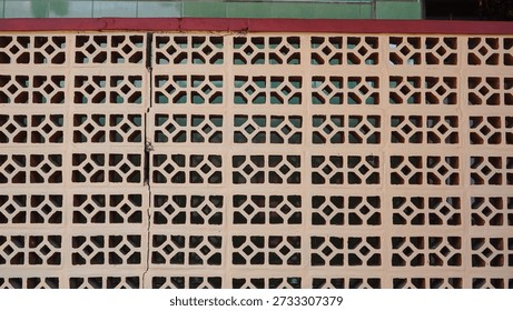 A wall with a pattern of holes and a red border. The wall is made of bricks and has a white trim