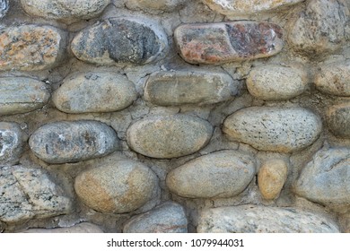 Wall of round granite stones, texture, background, close-up