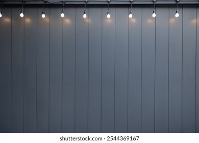 A wall with a row of lights on it. The lights are arranged in a straight line, with each light being spaced out evenly. The wall is made of a dark material