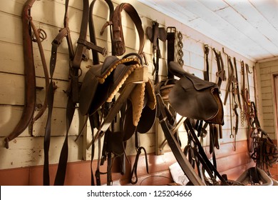 Wall of saddlery filled with horse equipment including saddles, bridles and old fashioned neck brace