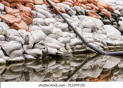 Wall Of Sandbags And Pump Discharge Tube Reflected By Puddle In Parking Lot Near The Illinois River: Documentary Detail For Themes Of Flood Control, Emergency Response, Preparedness