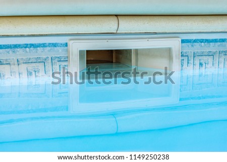 Wall skimmer equipment filtration swimming pool system with reflection on blue water pool.
