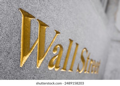 Wall Street gold lettering on a wall of a building in New York USA. Narrow depth of field, focus all the way to the left. Background image - Powered by Shutterstock