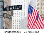 Wall street sign in New York with American flags and New York Stock Exchange background.